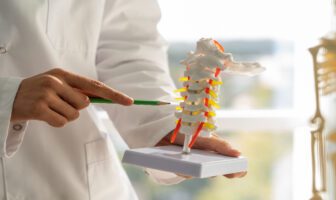 profissional-de-saúde-explicando-modelo-da-coluna-vertebral